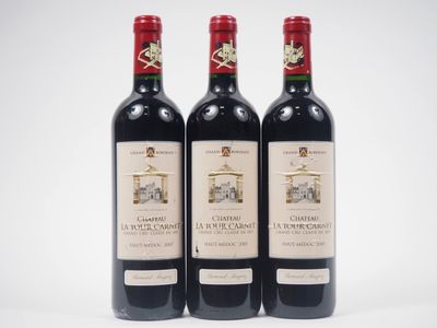 trois bouteilles de vin rouge posées l'une à côté de l'autre sur une surface blanche