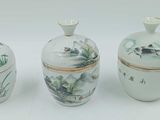 trois vases blancs ornés de motifs, posés sur une surface blanche