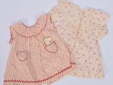 Deux vêtements pour bébé sont présentés sur une surface blanche