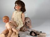 une poupée assise par terre, entourée d'autres poupées