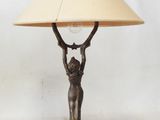 a bronze table lamp with a woman holding a lamp shade over her head