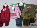 several baby clothes are hanging on a hanger on a wall