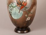 a vase with birds painted on it sitting on a table