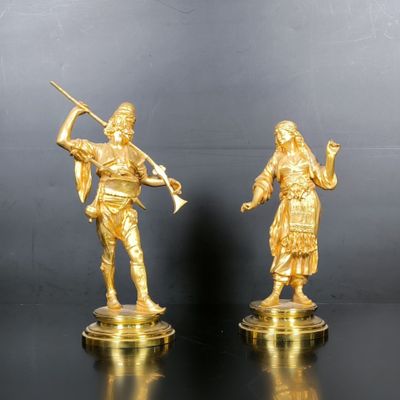 pair of antique brass figurines of a man and a woman holding a sword