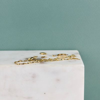une paire de boucles d'oreilles en or posée sur un bloc de marbre blanc