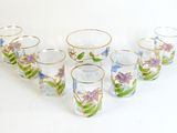 six shot glasses with flowers and leaves on them sitting on a white surface