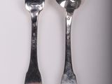 two spoons and a fork on a white surface