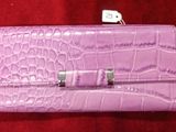 sac à main en cuir d'alligator violet avec des fermoirs argentés sur fond rouge