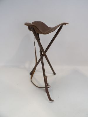 une image représentant un petit tabouret avec deux pieds en bois et une assise en cuir