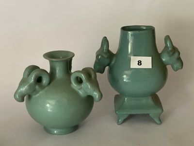 deux vases verts posés l'un à côté de l'autre sur une table