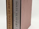 two books are stacked on top of each other on a white surface
