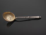 an antique silver spoon with a green stone in the center