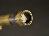 an antique brass telescope with a wooden handle on a black background