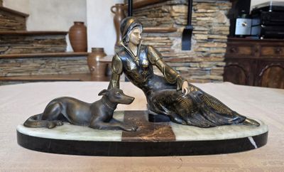 une statue représentant une femme et un chien assis sur une table