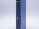 an old blue book sitting on top of a table next to a white wall