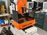 Une machine orange et noire se trouve dans une pièce où se trouvent de nombreuses autres machines