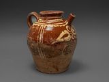 un vase marron orné d'un motif sur un fond gris
