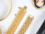 a lot of gold jewelry on a white surface