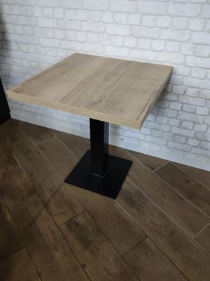 La table est en bois et possède un piètement en métal noir.