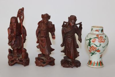 Trois figurines asiatiques sont posées à côté d'un vase sur une table