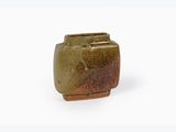 un petit vase vert posé sur une surface blanche