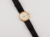 a gold and black watch on a white surface