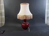 une lampe rouge avec un abat-jour blanc posée sur une table