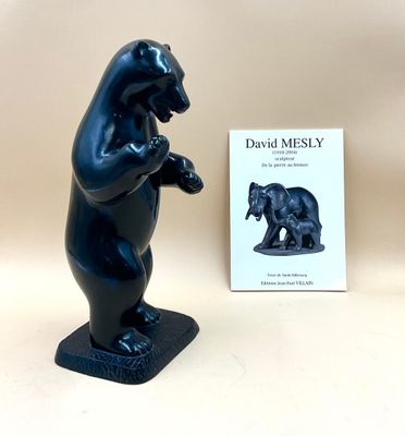 une statue d'ours noir posée à côté d'un livre sur une table