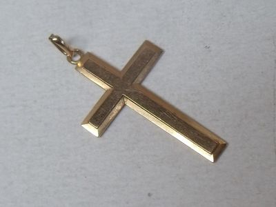 a gold cross that is laying on a white surface