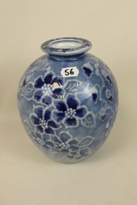 a blue vase with flowers on it sitting on a table
