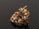 a close up of a gold and pearl broochle on a black surface