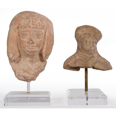 two pieces of clay head sculptures on stands on a white surface