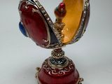 une boîte en forme d'œuf, rouge, jaune et bleue, posée sur un socle