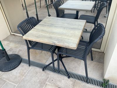 une table et des chaises à l'extérieur d'un restaurant, avec des parasols