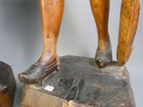 une statue en bois représentant une personne debout sur un rocher