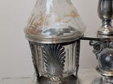 a silver plate with a glass bottle on top of it