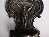 a silver sculpture of jesus on a cross on a stand