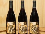 trois bouteilles de vin posées sur un tonneau en bois