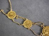 a close up of a necklace with gold coins on it