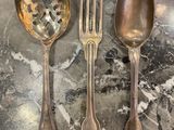 three silver spoons and two silver spoons on a table