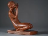 statue of a woman sitting on a wooden base with her hands on her head