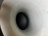 a white vase that has a black hole in it