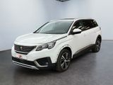 La voiture blanche est garée dans une grande pièce équipée d'un ventilateur de plafond.