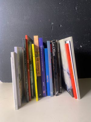 une pile de livres posée sur une table près d'un mur noir
