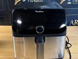 une friteuse à air chaud noire et argentée posée sur une table en bois