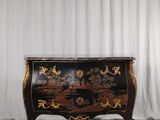 une photo d'une commode noire et dorée posée sur un parquet