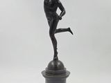 statue en bronze représentant un garçon tenant un ballon de basket sur un socle