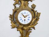 une horloge dorée accrochée au mur, avec des chiffres romains