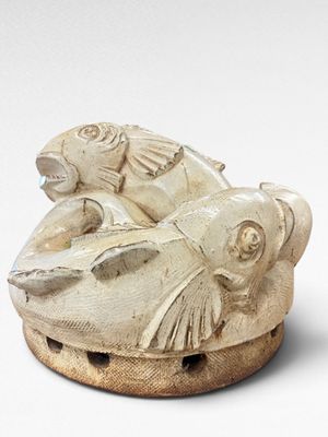 a white sculpture of a fish and a fish on top of it