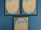 three magic the gathering cards are on a blue surface